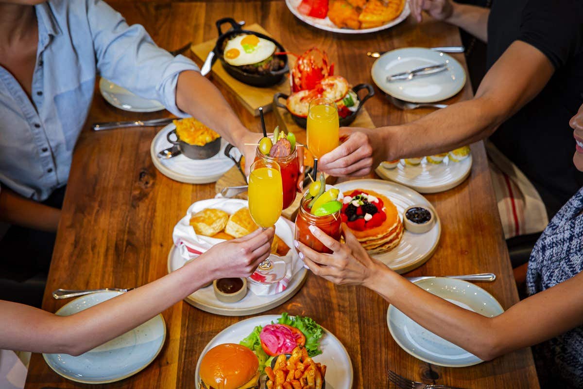 A group cheers-ing over a spread of dishes from the Yardbird restaurant.