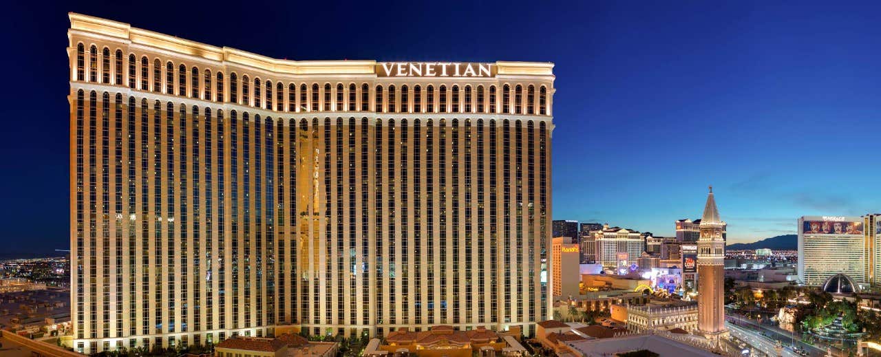 The Venetian hotel in Las Vegas illuminated at night, showcasing its iconic architecture and surrounding city lights.