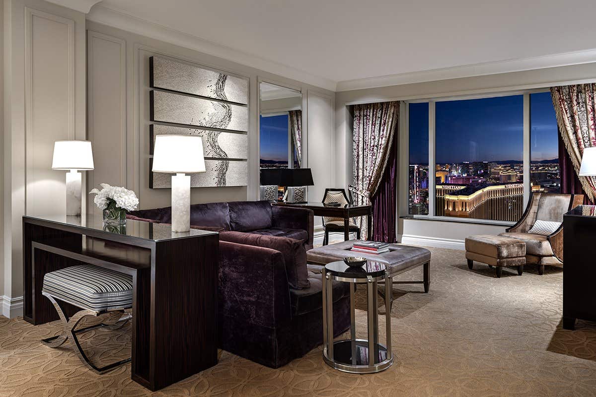The living room of a suite at night time with a view of Las Vegas.