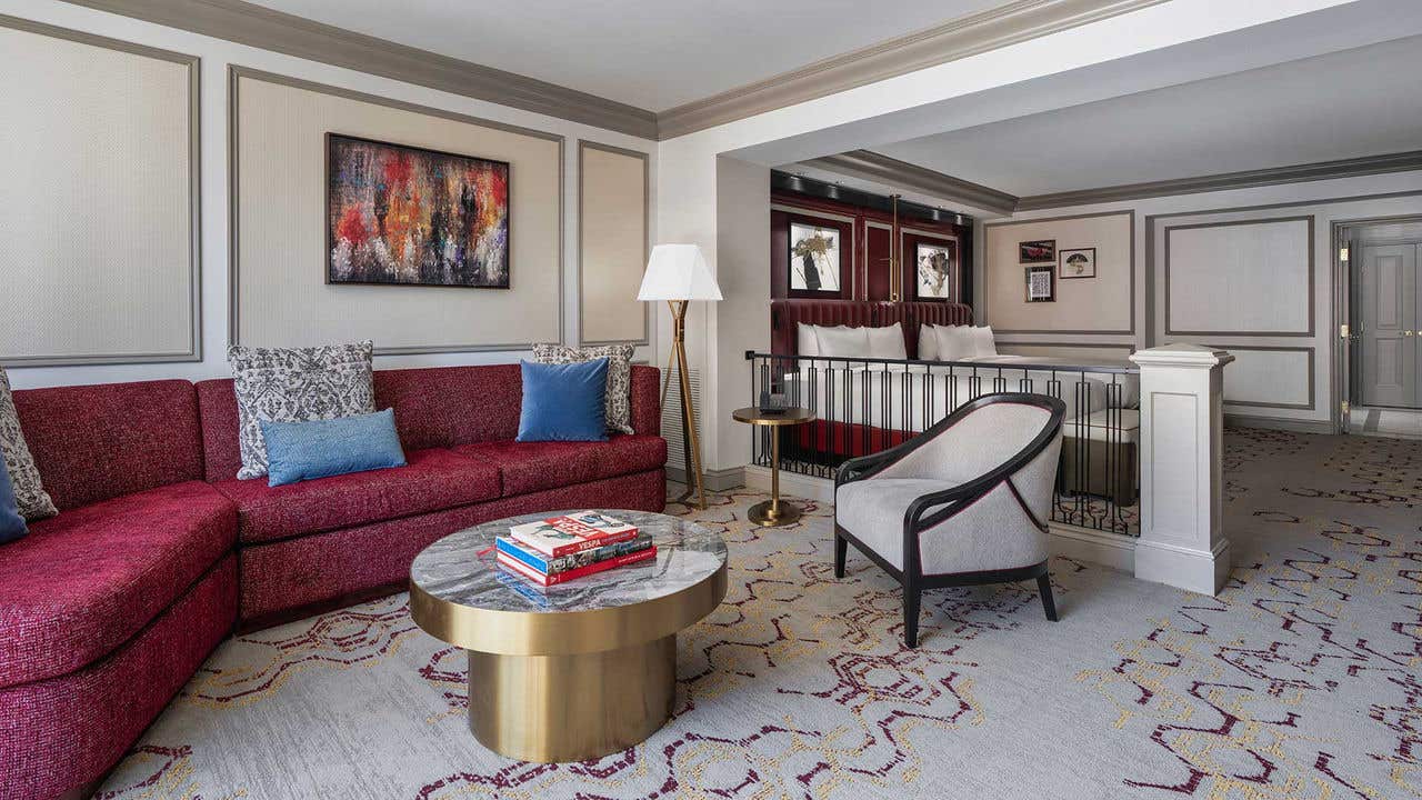 A hotel room with a living room area and two queen beds.