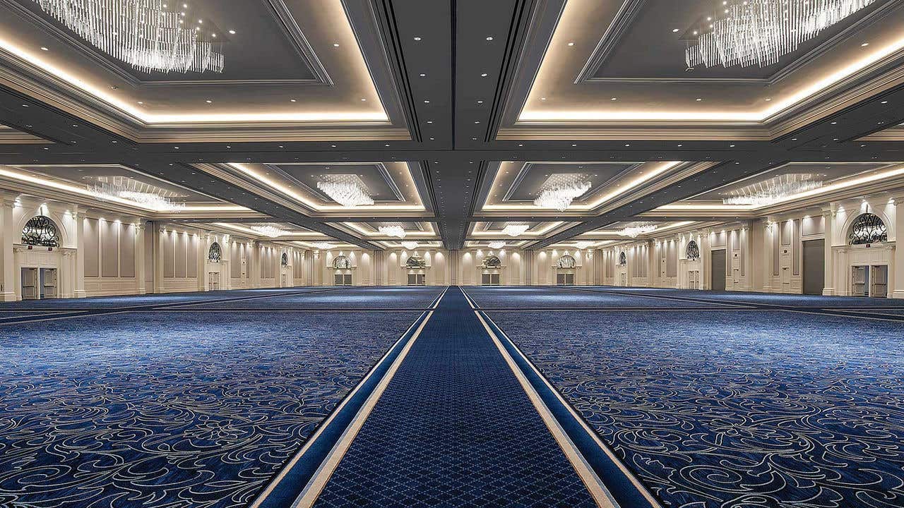 Large ballroom with blue carpet and chandelier above.